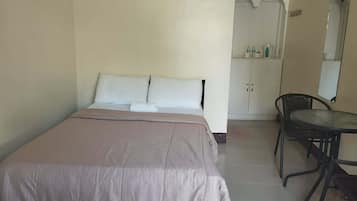 Una habitación sencilla con una cama, una mesita y una silla.