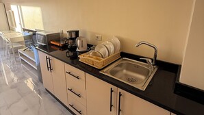 Een moderne keuken met een zwart aanrecht, een roestvrijstalen spoelbak en witte kastjes.