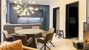 A modern kitchen with a central island, a dining area with a round table and chairs, and a wood-burning stove. - Saanan taika by Interhome (Enontekiö)