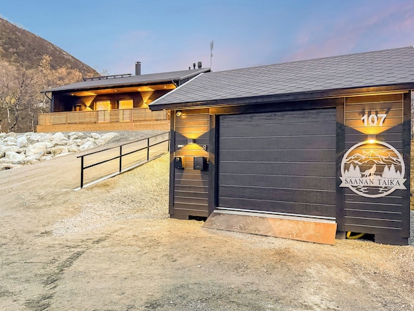 Una cabaña de madera con puerta de cochera numerada y vista a la montaña.