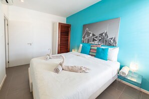 A hotel room with a bed, a painting on the wall, and a nightstand with a lamp. - Luxurious Apartment in Jan Thiel with Pool (Jan Thiel)