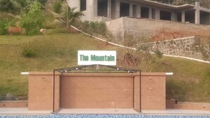 A sign reading "The Mountain" above a pool area with a modern building in the background. - Venkat's The MOUNTAIN by Redwings (Khalapur)