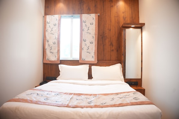 Una cama bien hecha con una colcha estampada, un cabecero de madera y una mesita de noche con una lámpara.