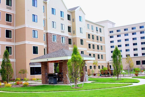 A multi-story hotel with a covered outdoor area featuring a grill and seating.