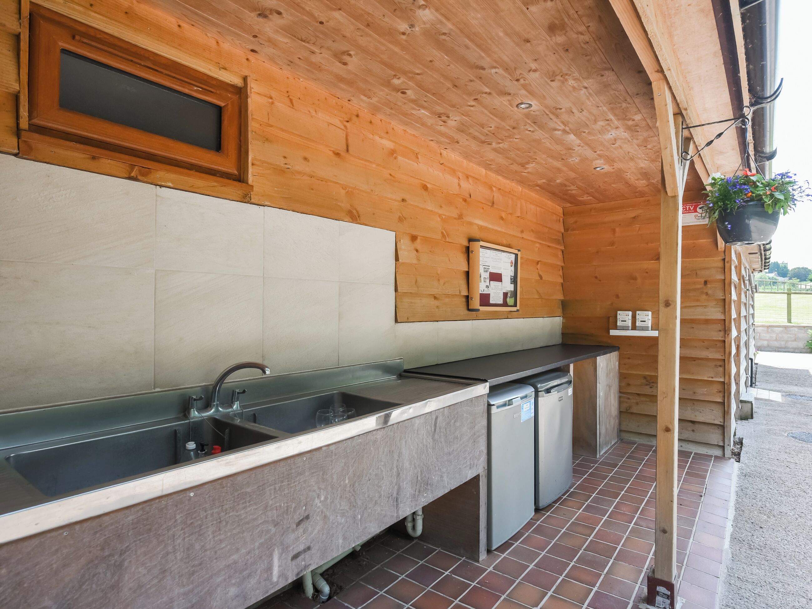 A wooden interior with a kitchen area, including a sink, countertop, and a small refrigerator.