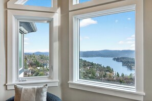 Ein Zimmer mit zwei großen Fenstern, das Blick auf einen See und die umliegende Landschaft bietet.