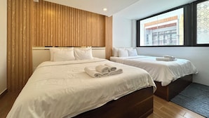 Ein Hotelzimmer mit zwei Betten, Holzvertäfelung an den Wänden, einem großen Fenster und Blick nach außen.