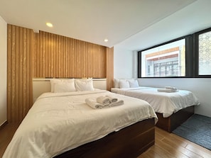 A hotel room with two beds, wooden paneling on the walls, a large window, and a view of the outside. - Dream Land (Cau Kho)