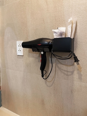 A hair dryer mounted on a wall with a power outlet and a charging cable. - Dream Land (Ho Chi Minh City)