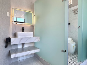 A modern bathroom with a marble sink, a mirror with a gold frame, a black telephone, and a toilet with a white design. - Dream Land (Cau Kho)