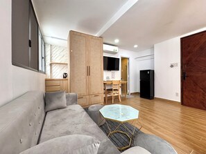 A modern living room with a sofa, a glass coffee table, and a wooden wardrobe. - Dream Land (Cau Kho)