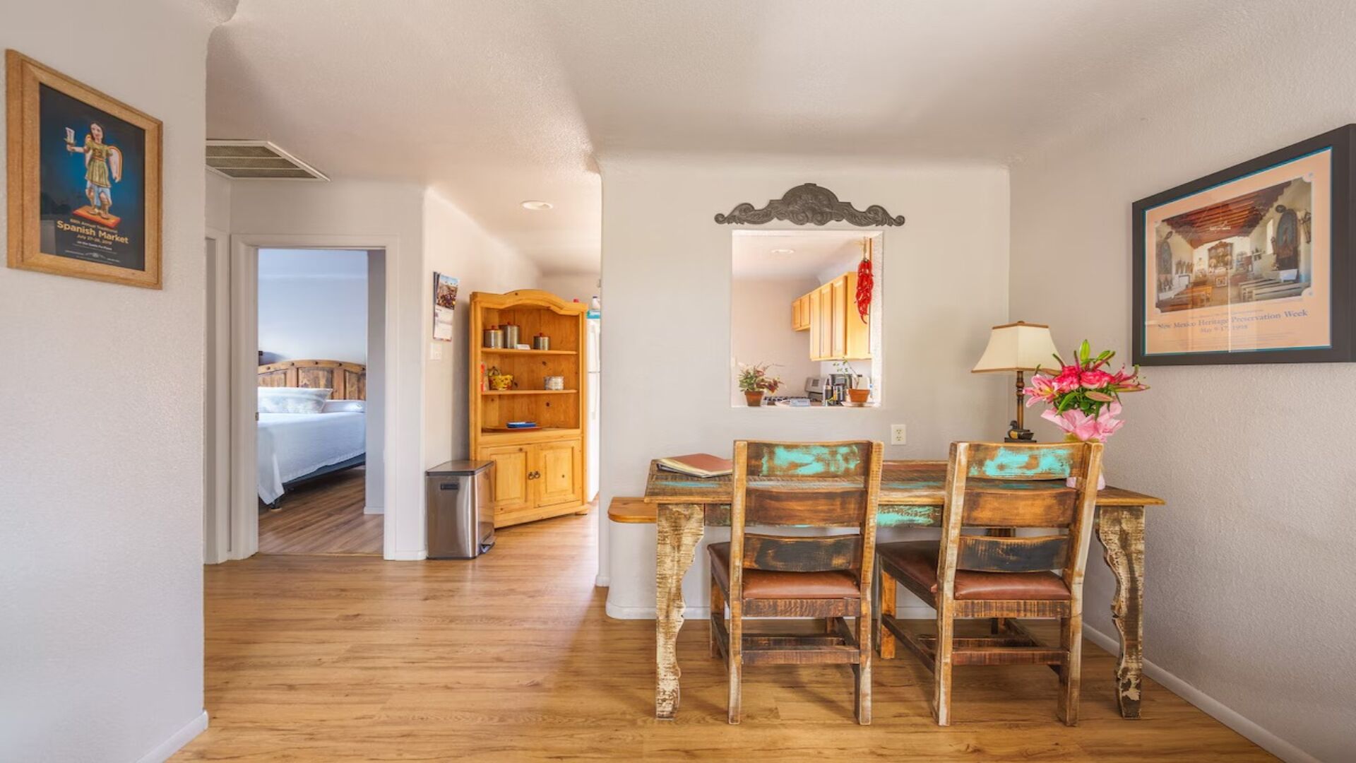 Un comedor con una mesa y sillas de madera, un mueble pequeño y un espejo sobre la mesa.