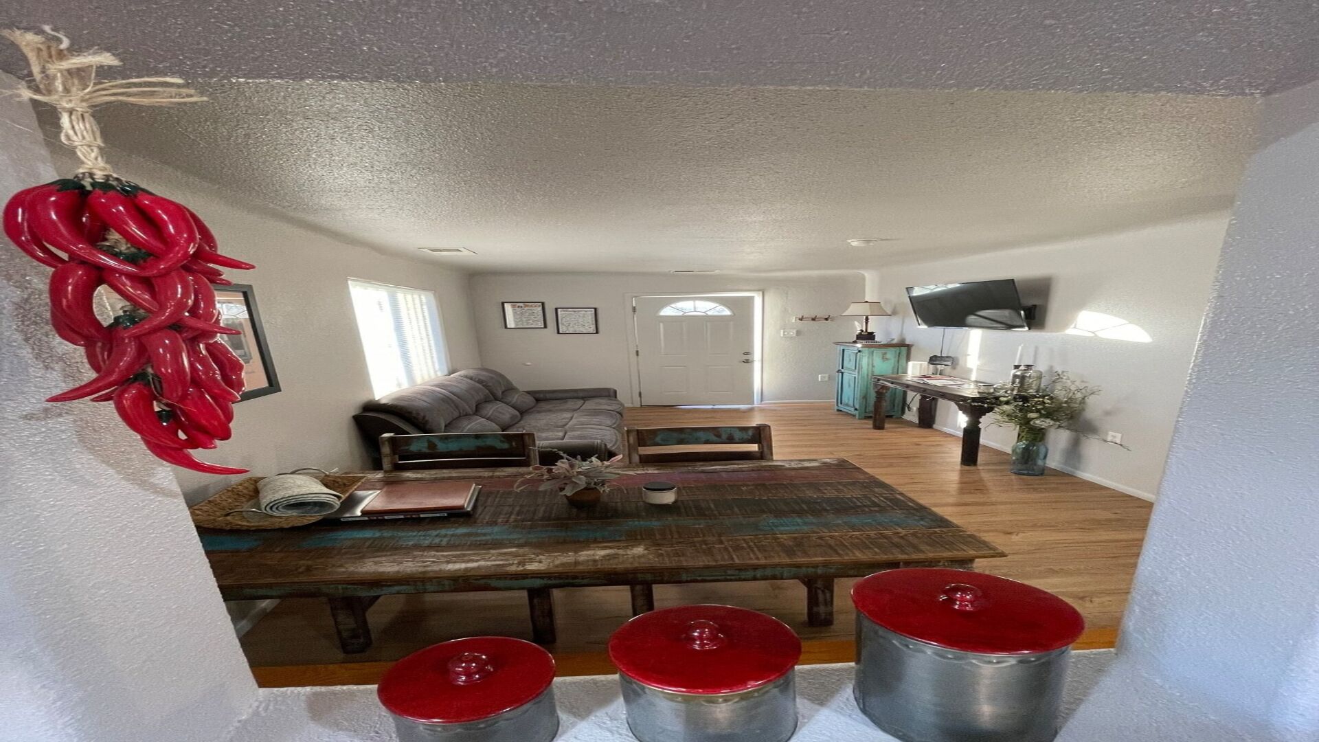 A spacious living area with a wooden dining table, a sofa, and a television.