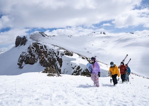 Eine Gruppe von Wanderern auf einem verschneiten Berg mit Felsformationen und blauem Himmel.