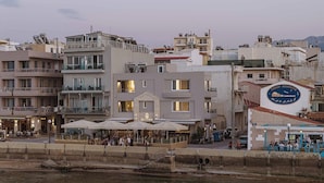Een hotel aan het water met terras, een bord dat een restaurant aangeeft en uitzicht op zee.