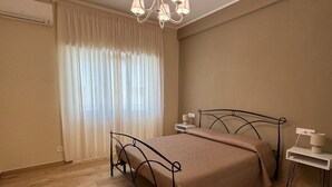 Un dormitorio con cama, mesitas de noche, lámpara y ventana con cortinas.