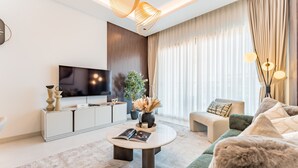 Ein modernes Wohnzimmer mit Flachbildfernseher, rundem Couchtisch, einer Couch und einer Topfpflanze.