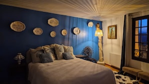 Une chambre avec un grand lit, un mur bleu et plusieurs assiettes décoratives.