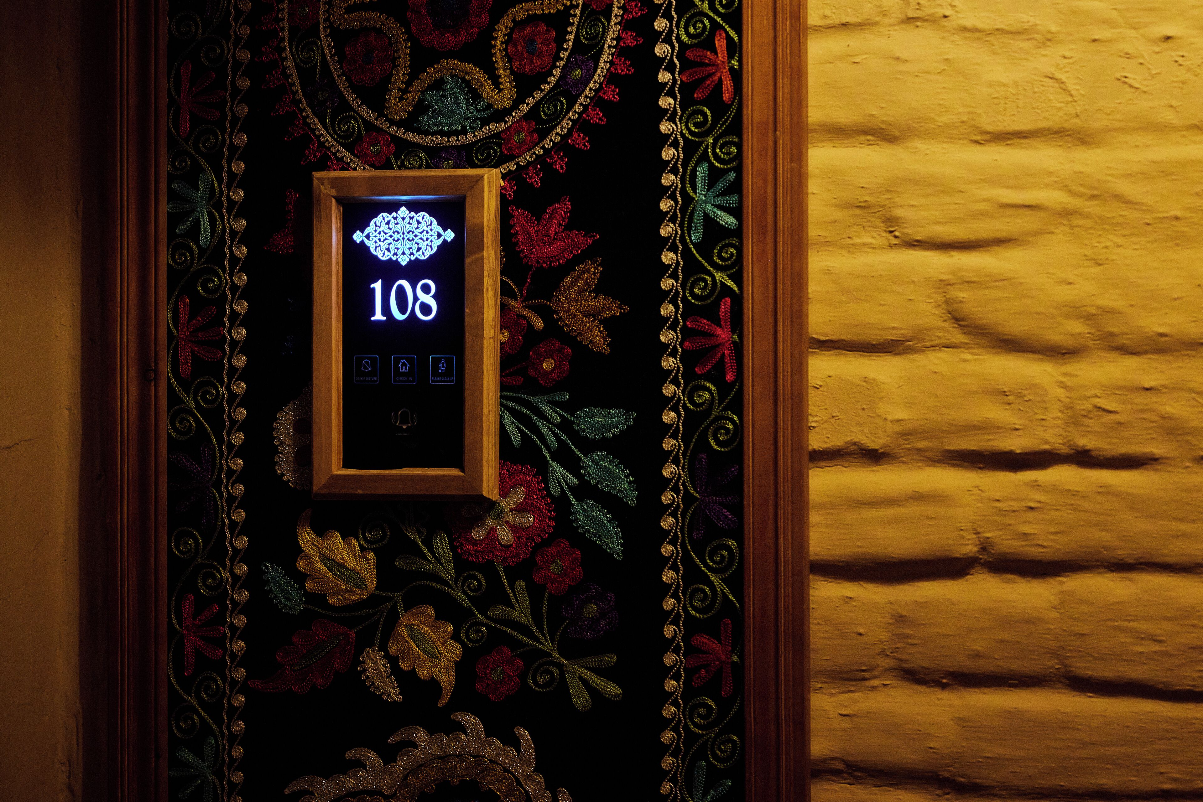 Une serrure numérique ornée d’un motif floral décoratif et portant le numéro 108, fixée à un mur.
