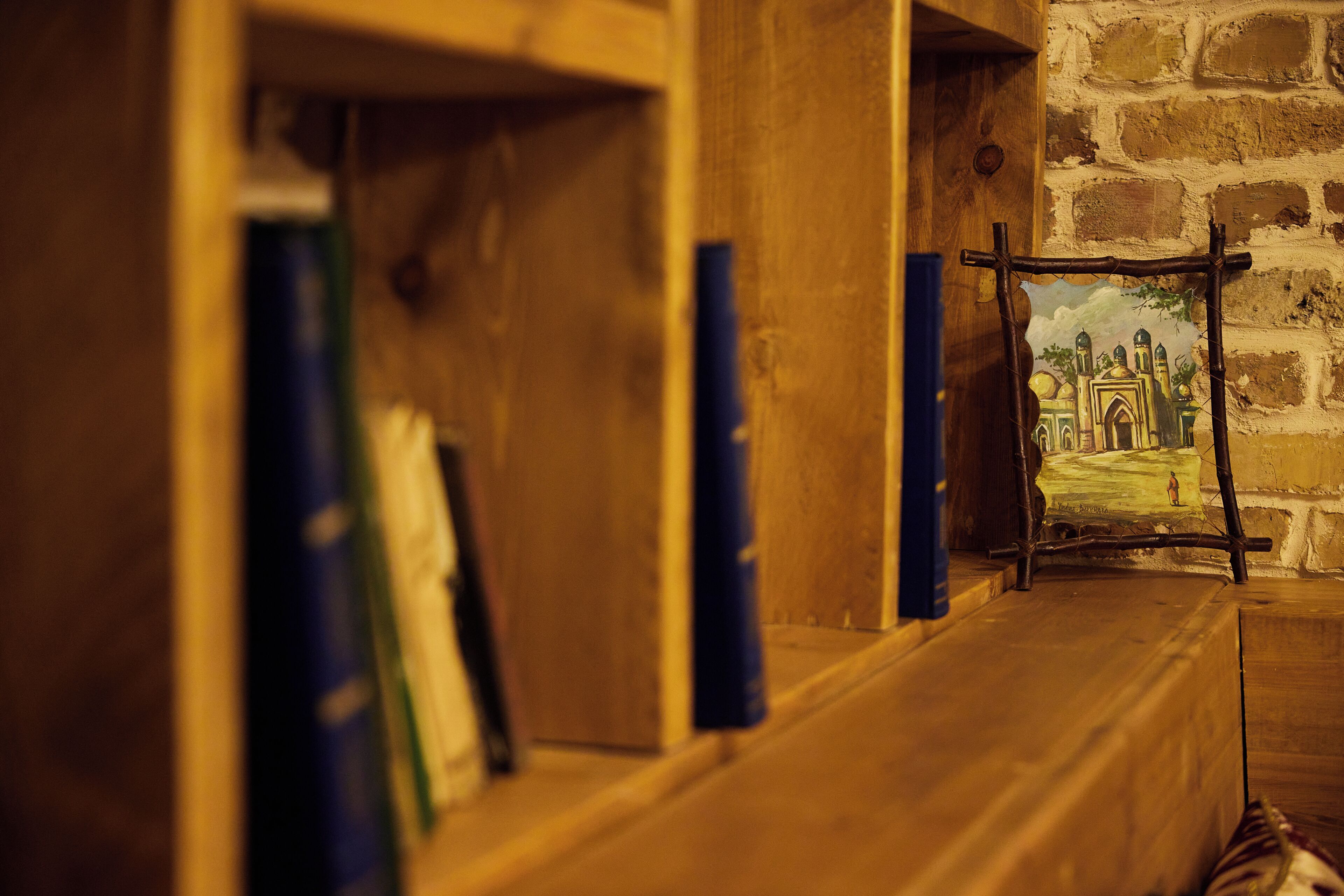 Une pièce avec une bibliothèque en bois, un tableau au mur et un mur en pierre.