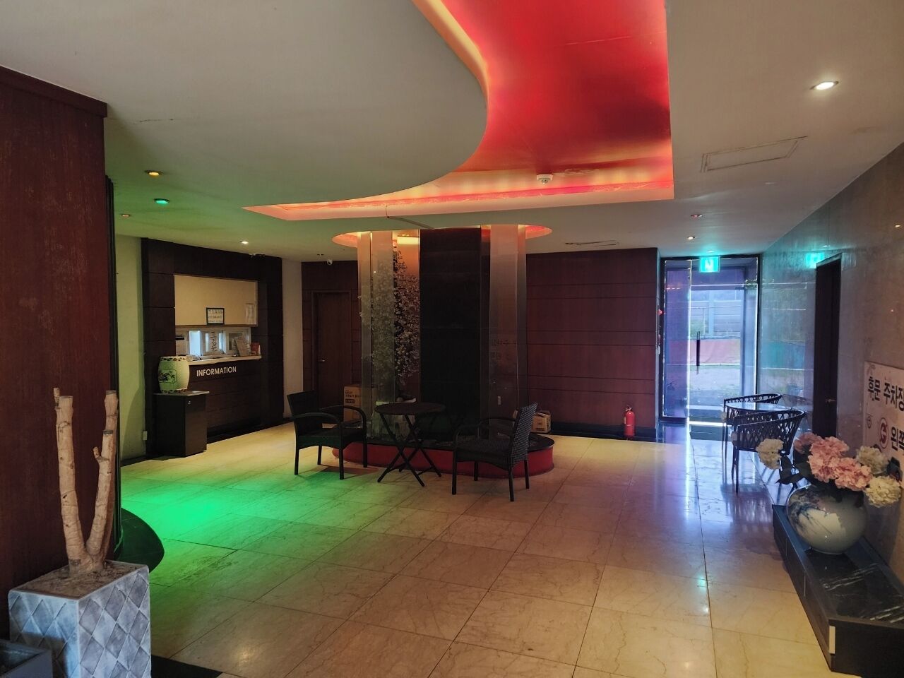 A lobby with a reception desk, seating area, and a large vase with flowers.