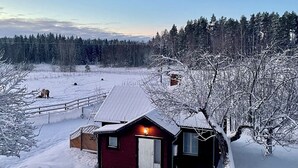 A small cabin with a red exterior, a white door, and a small porch area. - Valstabacken -charming countryside cottage in peaceful Swedish nature (Möklinta)