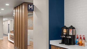 Vestíbulo de hotel con una recepción, una estación de café y un letrero que indica el área de mercado.