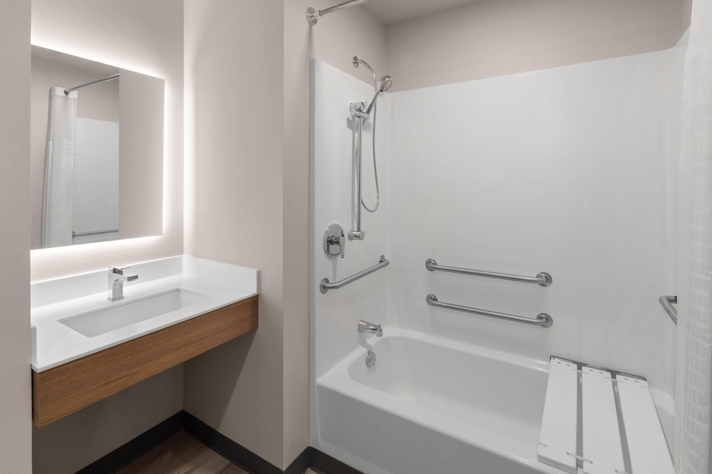 A modern bathroom with a white sink, mirror, and shower area.