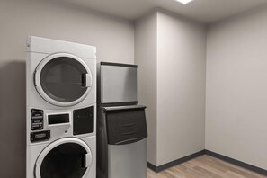 A laundry room with a front-loading washer and dryer, a small refrigerator, and a wall-mounted drying rack. - Microtel Inn & Suites by Wyndham Ephrata (Ephrata)