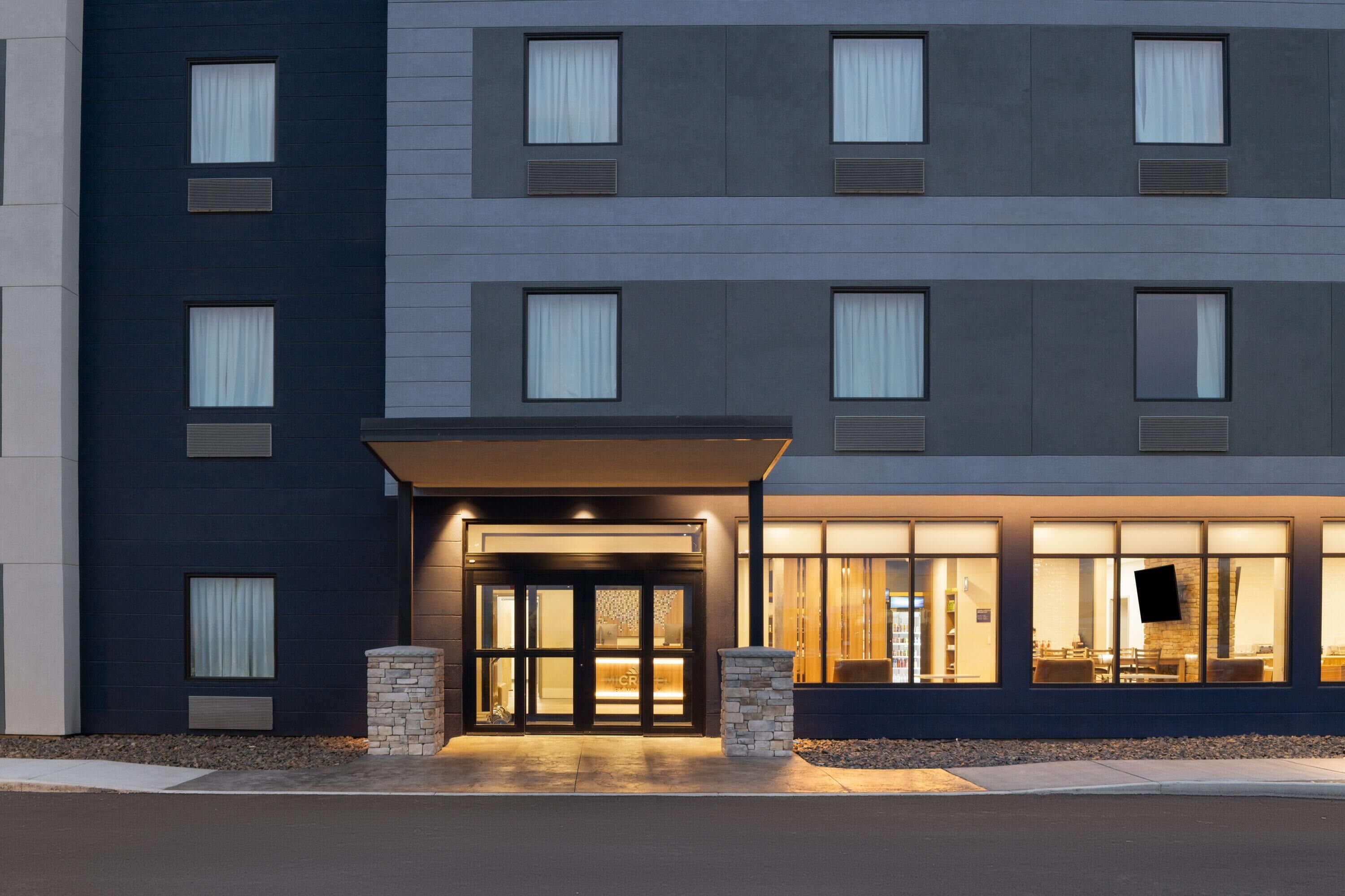 A multi-story hotel with a dark facade, large windows, and a well-lit entrance.