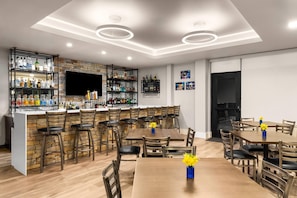 A bar area with multiple seating options, a television, and a variety of liquor bottles. - Microtel Inn & Suites by Wyndham Ephrata (Ephrata)