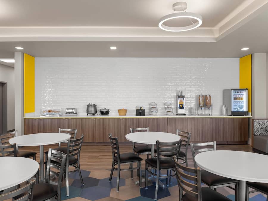 A modern kitchen area with a white brick backsplash, stainless steel appliances, and a digital menu display.