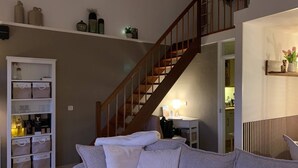 A living room with a staircase, a white storage unit, and a cozy sofa. - Forest cottage by the sea (Sint Maartensvlotbrug)