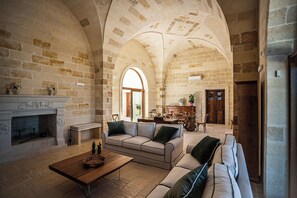 Amplia sala de estar con chimenea, un conjunto de sofás y un comedor con una mesa y sillas de madera.