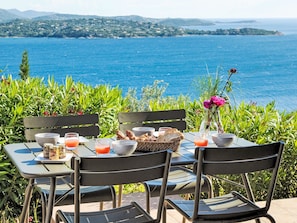 A table set outdoors with a view of the sea, surrounded by greenery. - Vacation home Anto by Interhome (Porto Vecchio)