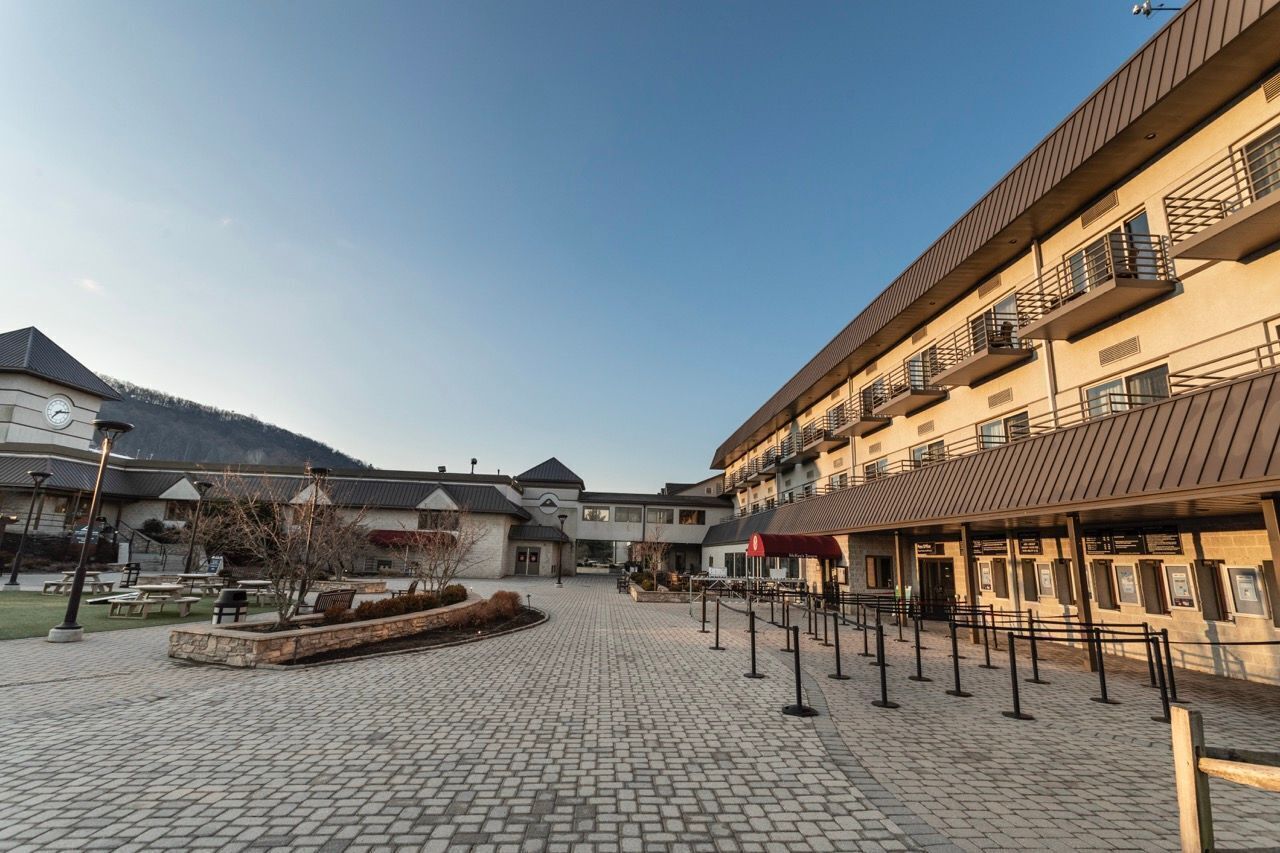 A courtyard with a cobblestone floor, outdoor seating, and a building with balconies.