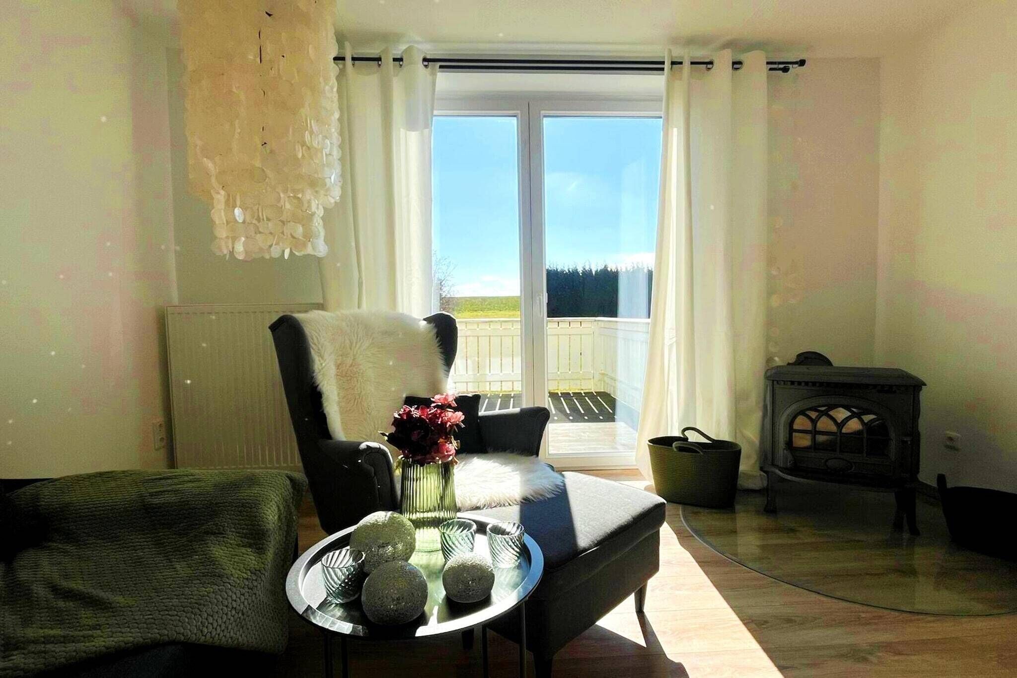 Ein Zimmer mit einer Couch, einem kleinen Tisch mit Dekoration, einer Heizung, einem Fenster mit Vorhängen und einem Kamin.