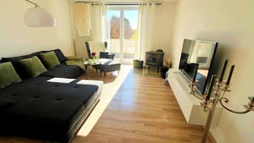 Ein modernes Wohnzimmer mit einer Couch, einem Sessel, einem Fernseher und einem Kamin.