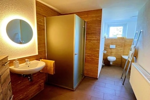 A modern bathroom with a round mirror, a sink, and a toilet.