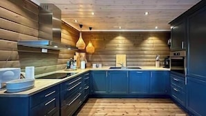 Une cuisine moderne avec des armoires bleues, un plafond en bois et des luminaires suspendus.