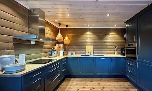 Une cuisine moderne avec des armoires bleues, un plafond en bois et des luminaires suspendus.