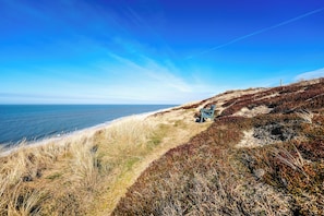 Paisatge costaner amb una cadira sobre un camí herbós amb vista al mar.