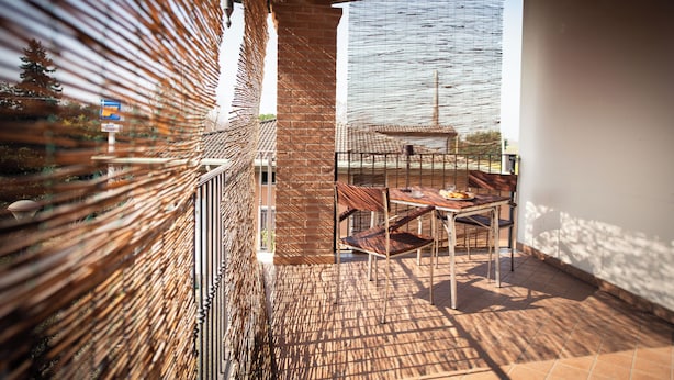 Un balcone con un muro in mattoni, una ringhiera in metallo e un tavolo con sedie.