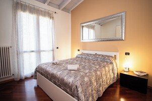 Una camera da letto con un letto, un comodino, uno specchio e una finestra con tende.