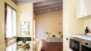 Una cucina moderna con elettrodomestici in acciaio inossidabile, una zona pranzo con tavolo in vetro e vista sul soggiorno.