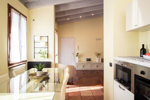 Una cucina moderna con elettrodomestici in acciaio inossidabile, una zona pranzo con tavolo in vetro e vista sul soggiorno.