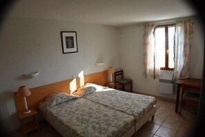 Une chambre d’hôtel avec un lit double, des tables de chevet, un bureau et une fenêtre avec des rideaux.