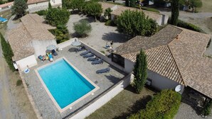 Piscina com espreguiçadeiras e área coberta, cercada por árvores e edifícios.