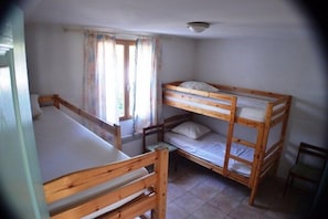 A room with bunk beds, a window with curtains, and a chair. - Villa La Treille 1 avec piscine près des gorges de l’Ardèche (Grospierres)
