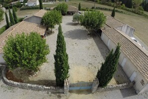 A courtyard with a gravel path, surrounded by buildings with tiled roofs and stone walls. - Villa La Treille 1 avec piscine près des gorges de l’Ardèche (Grospierres)